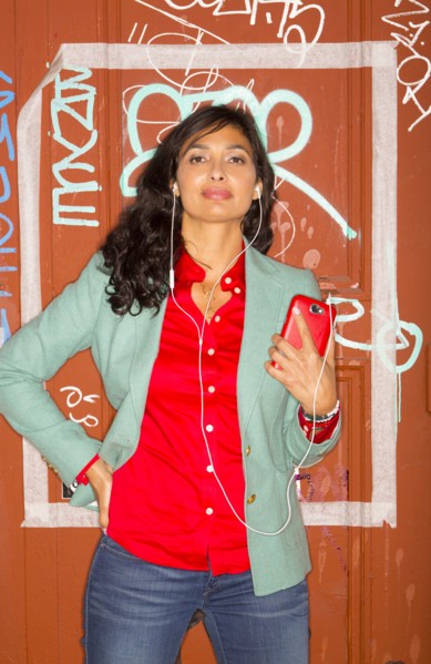 Mixed race woman listening to headphones against graffiti wall
