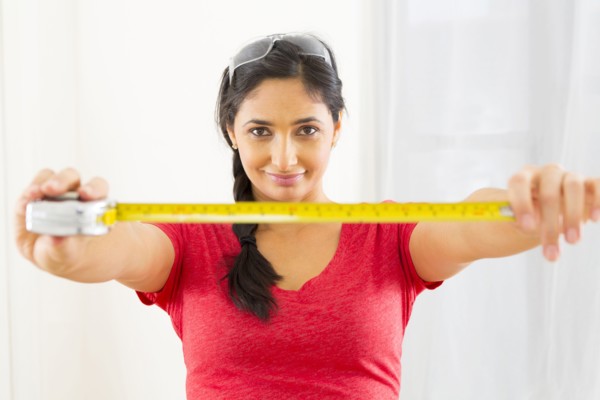 Mixed race woman using measuring tape