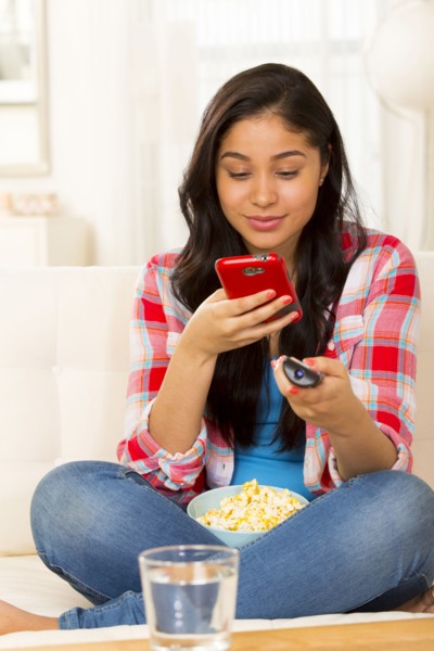Hispanic woman using cell phone on sofa