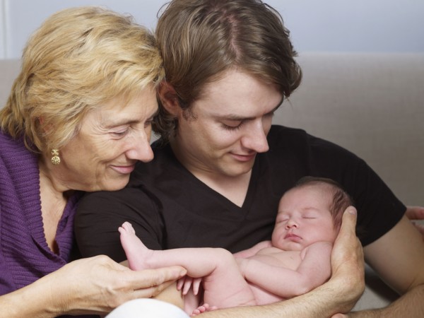 Senior mother and son cuddling newborn baby