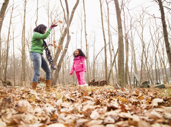 Mother and daughter playing with autumn leaves