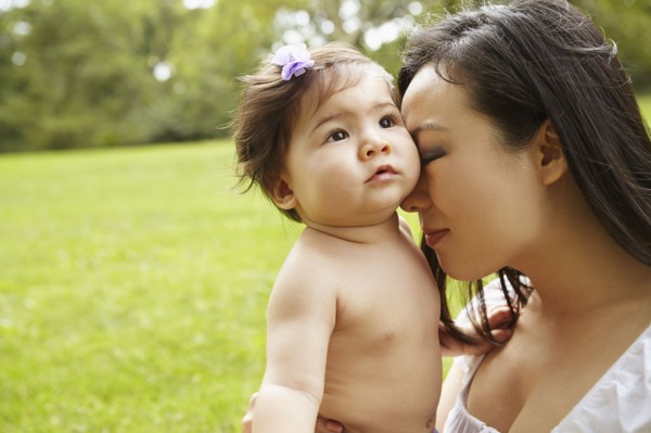 Mother cradling baby girl in park