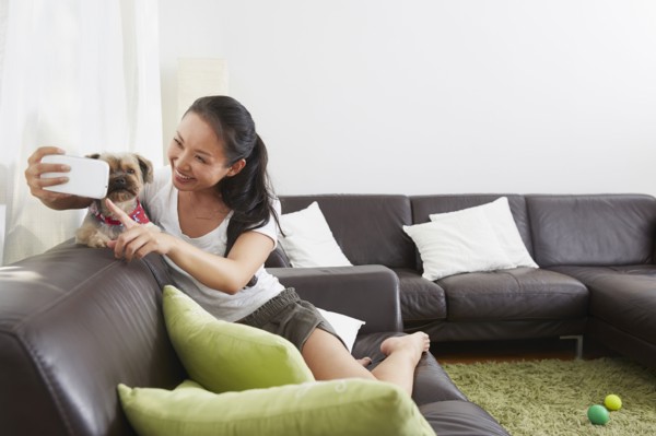 Chinese woman taking cell phone selfie with dog in living room
