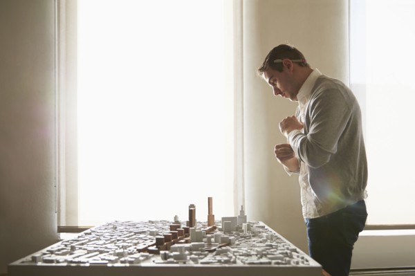 Caucasian architect examining urban model in office