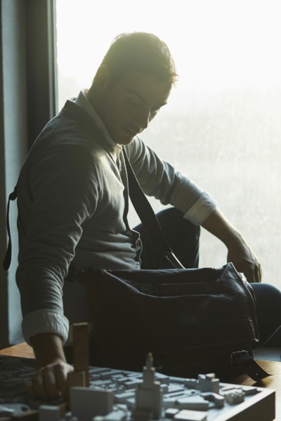 Caucasian architect at office window examining urban model