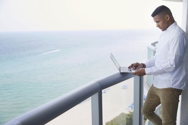 Black businessman using laptop on balcony