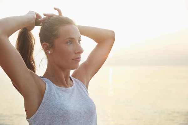 Athlete tying hair in ponytail on beach