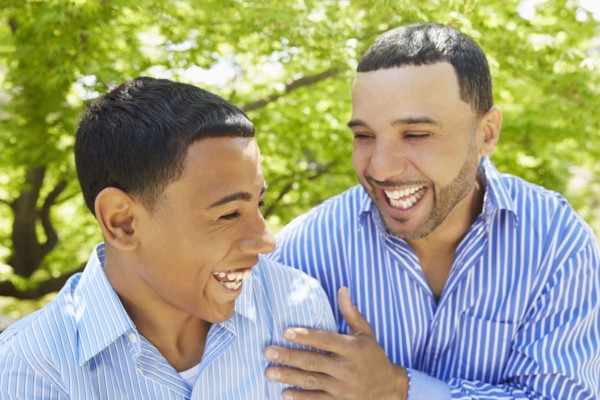 Hispanic father and son laughing in park