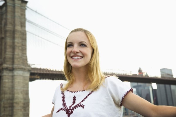 Caucasian woman smiling under Brooklyn Bridge