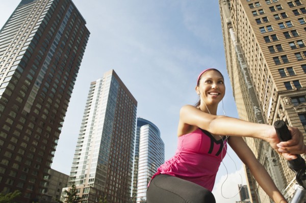 Hispanic woman riding bicycle under highrise buildings