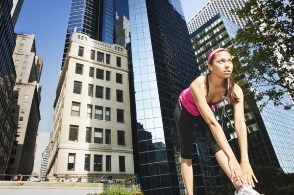 Hispanic woman stretching under highrise buildings