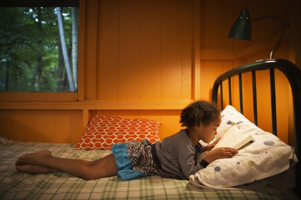 Mixed race girl reading on bed