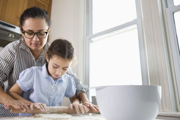 Mother teaching daughter to bake in kitchen