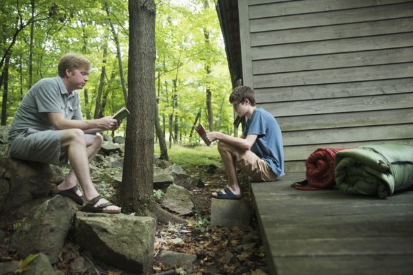Caucasian father and son reading books at cabin