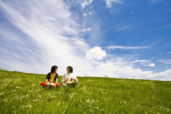 Asian couple playing drums in meadow