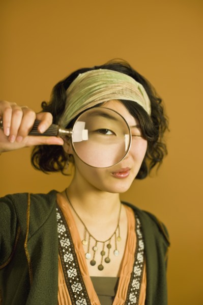 Asian woman looking through magnifying glass