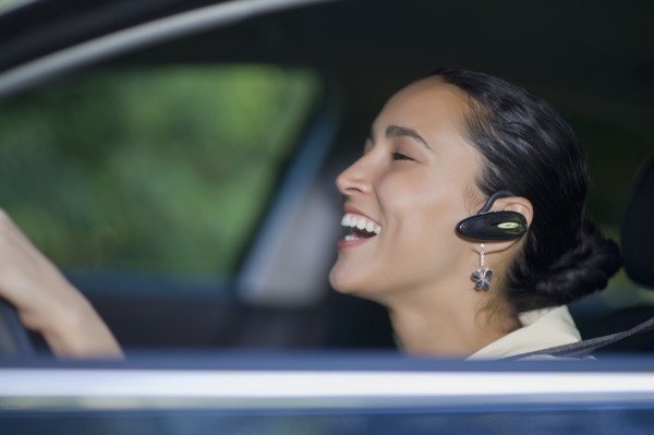 Hispanic woman driving with hands-free cell phone device