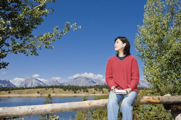 Japanese woman sitting on fence with mountains in background