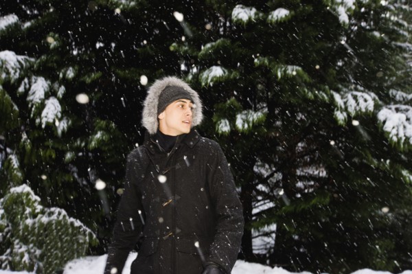 Mixed race man in hooded coat outdoors in snowfall