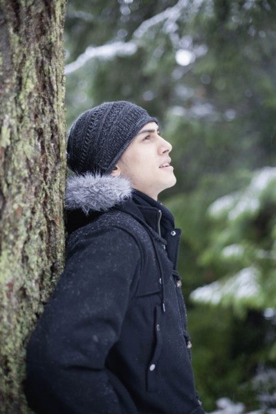 Mixed race man leaning against tree trunk