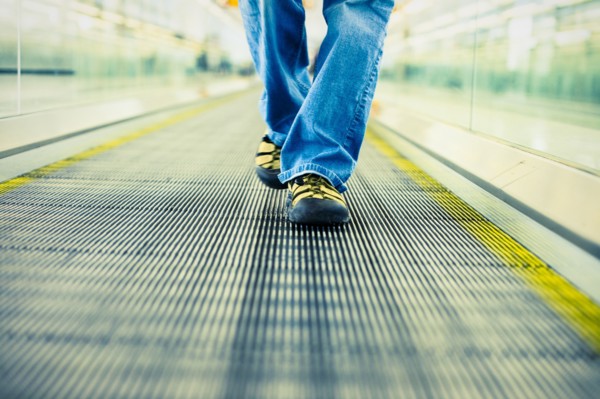 Legs of Japanese woman wearing jeans walking on moving walkway