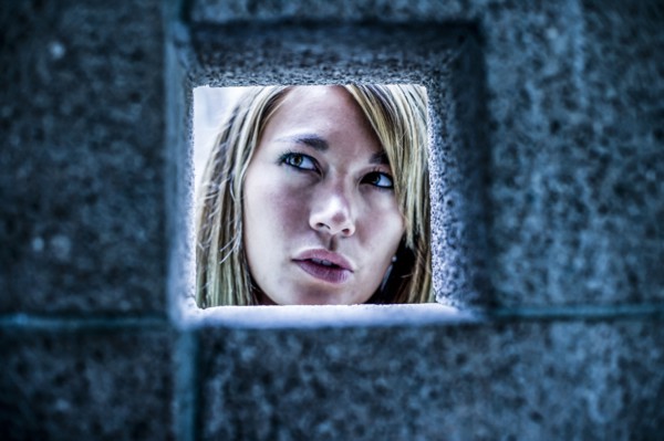 Curious Mixed Race woman looking through stone wall