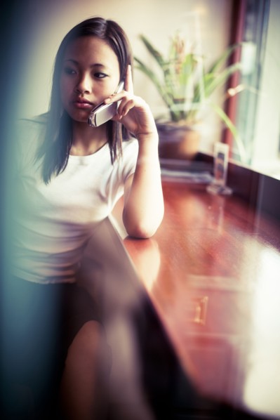 Serious Asian girl talking on cell phone