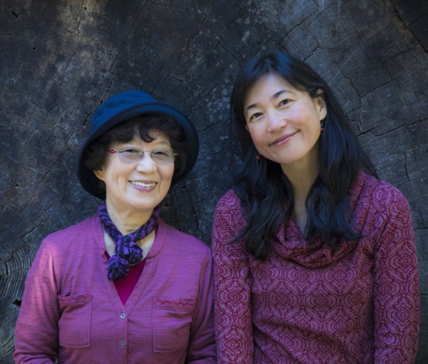 Older Japanese mother and daughter posing at tree slice
