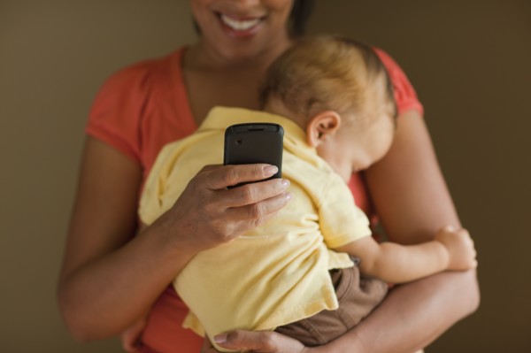 Mother text messaging while holding sleeping child