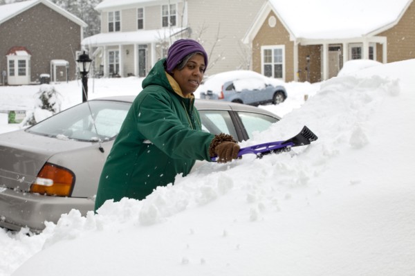African American woman scraping snow from windshield