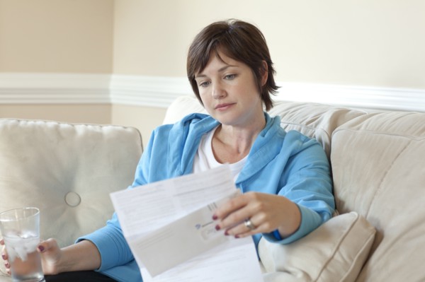 Caucasian woman on sofa reviewing bills