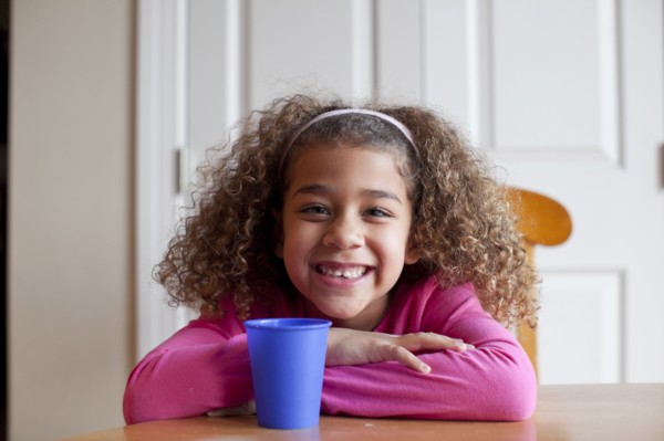 Grinning mixed race girl sitting with cup