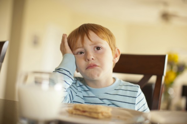 Caucasian boy pouting at dinner table