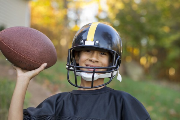 Mixed race boy playing football outdoors