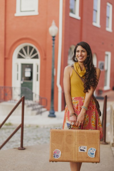 Mixed race woman carrying suitcase on city street