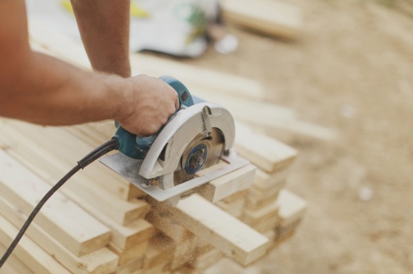 Caucasian construction worker sawing wood planks