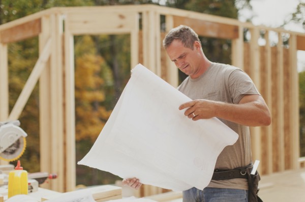 Caucasian construction worker reading blueprints on site