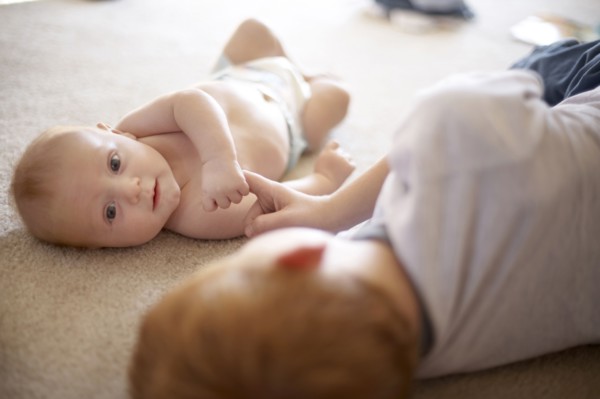Caucasian boy playing with baby brother on carpet