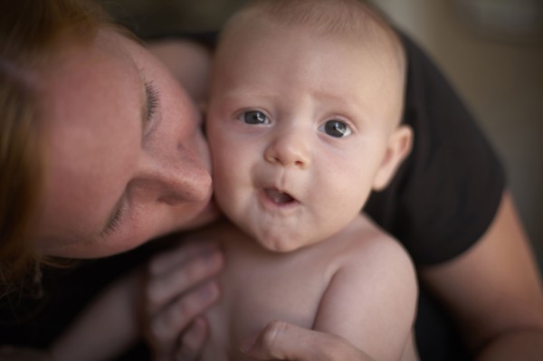Caucasian mother kissing baby's cheek