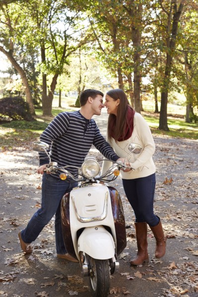 Couple kissing over scooter in suburban neighborhood