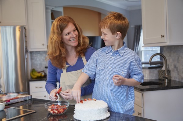 Caucasian mother and son decorating cake in kitchen