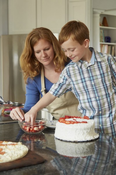 Caucasian mother and son decorating cake in kitchen