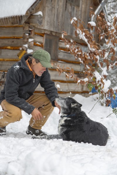 Mixed race man petting dog in snow