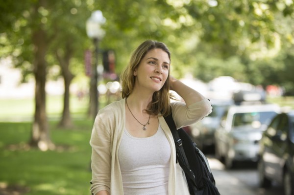 Caucasian student carrying backpack on sidewalk