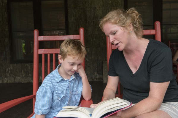 Caucasian mother and son reading on patio