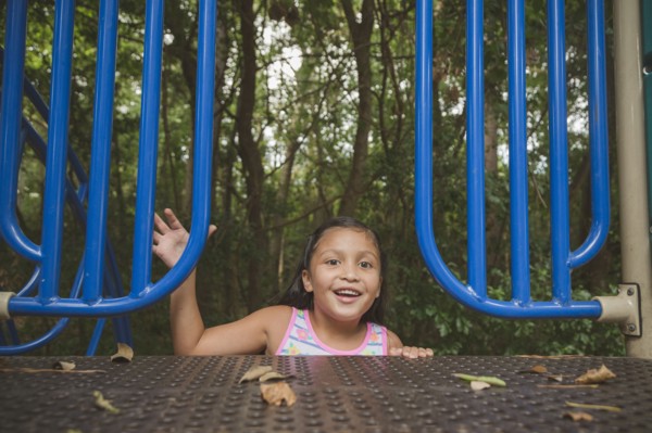 Smiling Hispanic girl reaching on playground