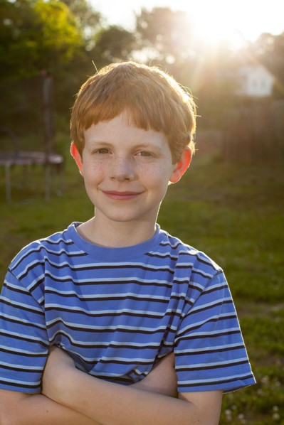 Smiling Caucasian boy standing in sunny backyard