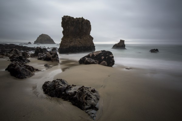 Rock formations and ocean waves on sandy beach