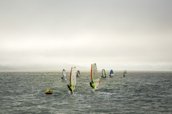Windsurfers on ocean under cloudy sky