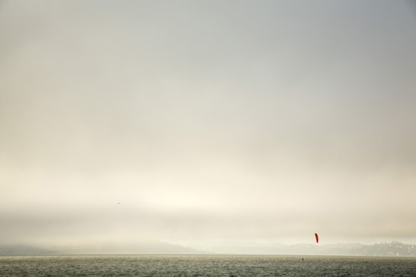 Kiteboarder on ocean under cloudy sky